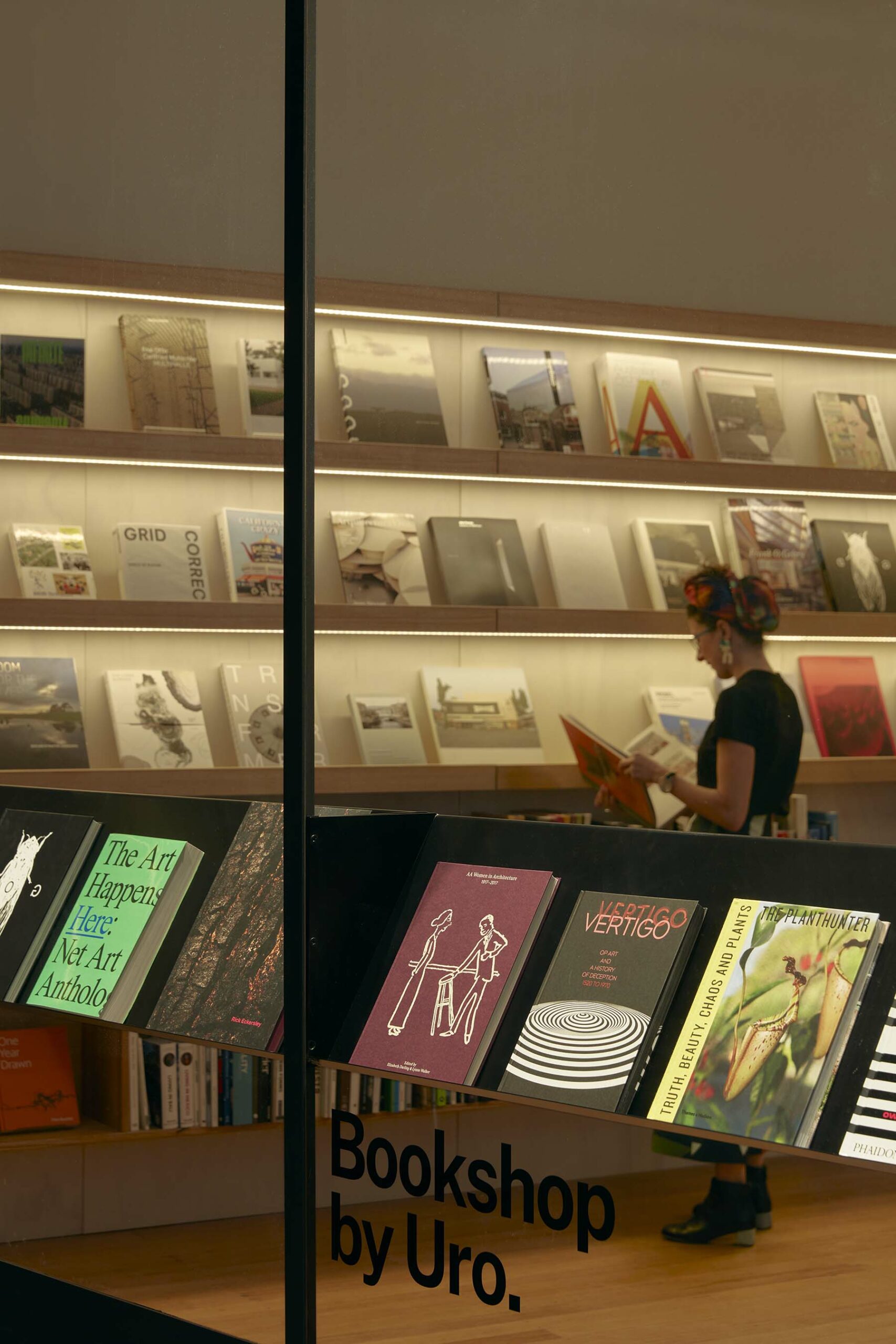 The window of Bookshop by Uro. Walls and shelves of books are visible, and a person is browsing the books available.